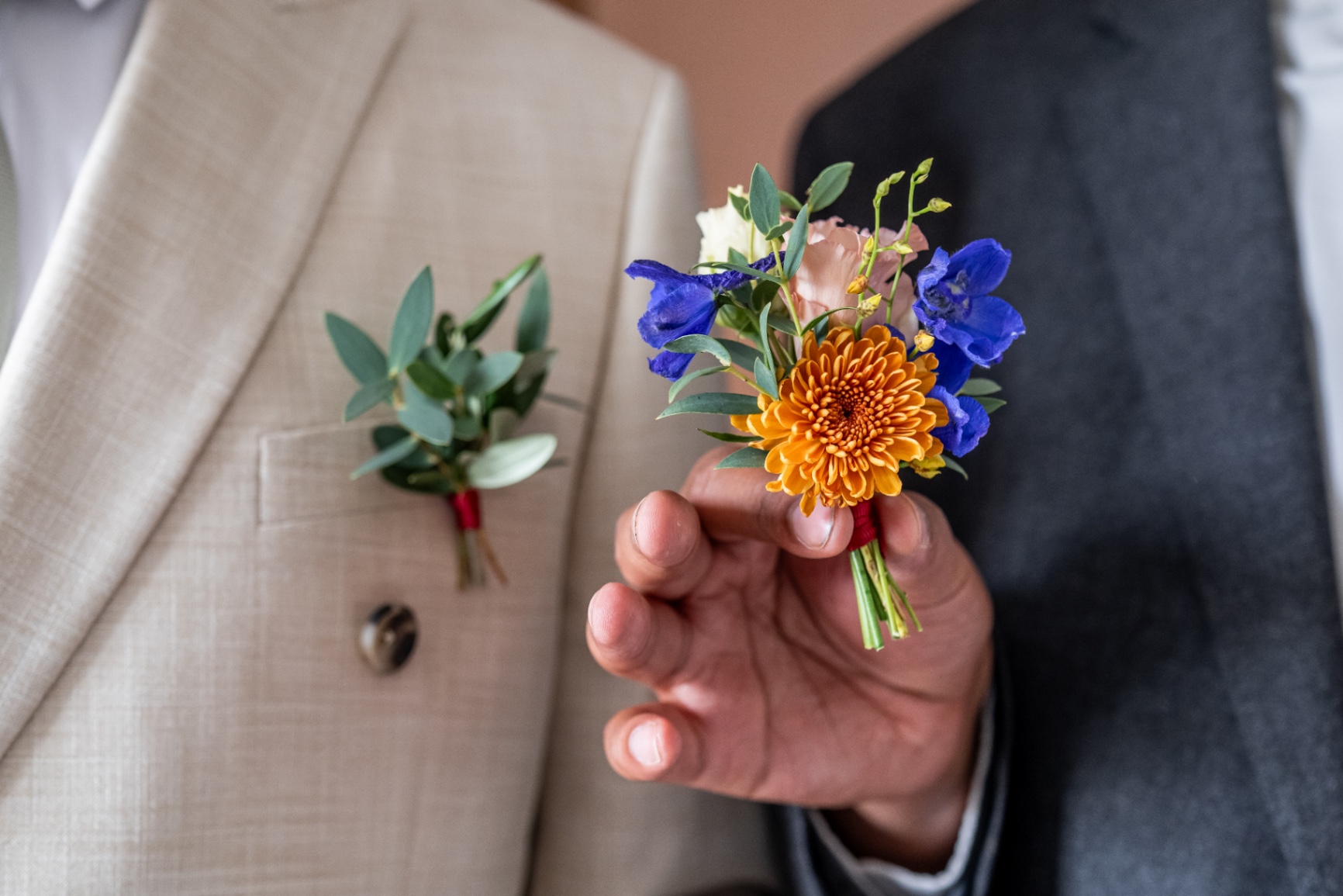 Boutonnière marié fleurie et coloré avec en arrière plan la boutonnière des témoins faite de euillage.jpeg
